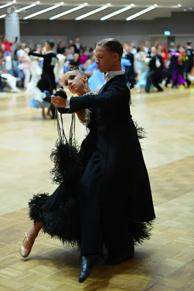 Dancesport competitor: Male dancer: black ballroom tailcoat, white shirt collar, black trousers, and bl