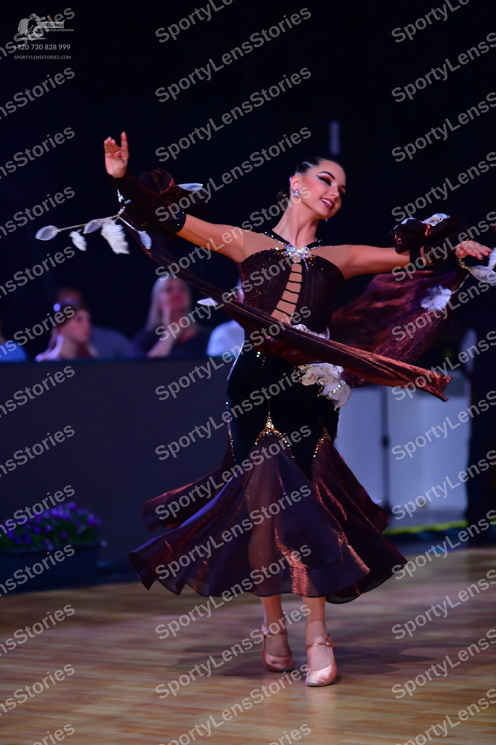 Dancesport competitor: Female dancer: dark brown/maroon latin dress with a velvet bodice, cutouts, and