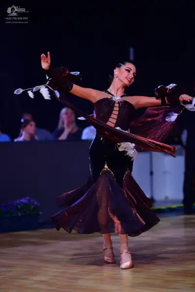 Dancesport competitor: Female dancer: dark brown/maroon latin dress with a velvet bodice, cutouts, and 
