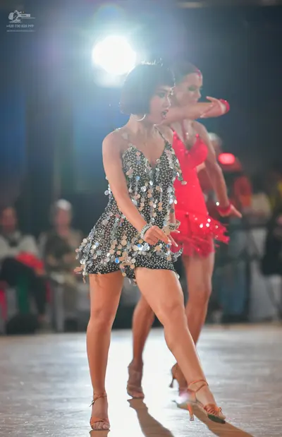 Dancesport competitor: Female dancer in foreground: black latin dress decorated with large silver sequi
