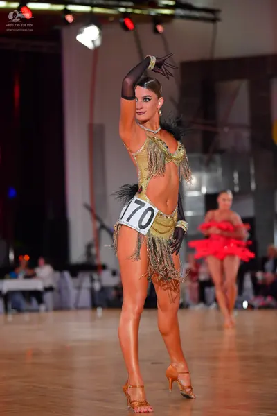 Dancesport competitor #170: Female dancer 1: gold latin dress with sequins and long fringe, and black sheer 