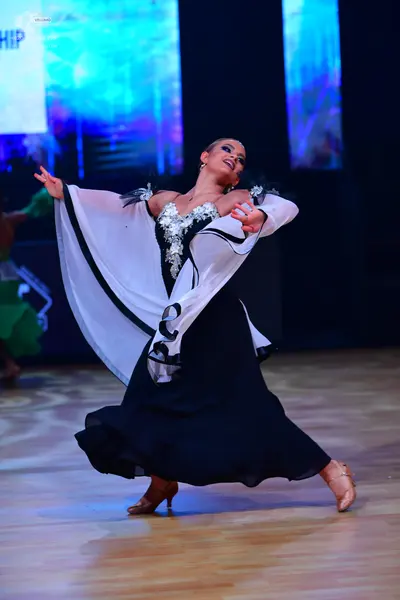 Dancesport competitor: Female dancer: black ballroom gown with a voluminous skirt, featuring a heavily 