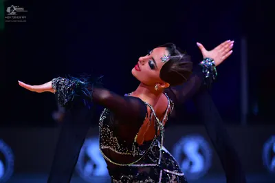 Dancesport competitor: Female dancer: black Latin dress heavily embellished with silver sequins and rhi
