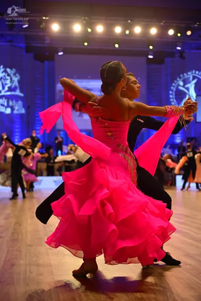 Dancesport competitor: Female dancer: magenta ballgown with an embellished bodice and a voluminous, mul