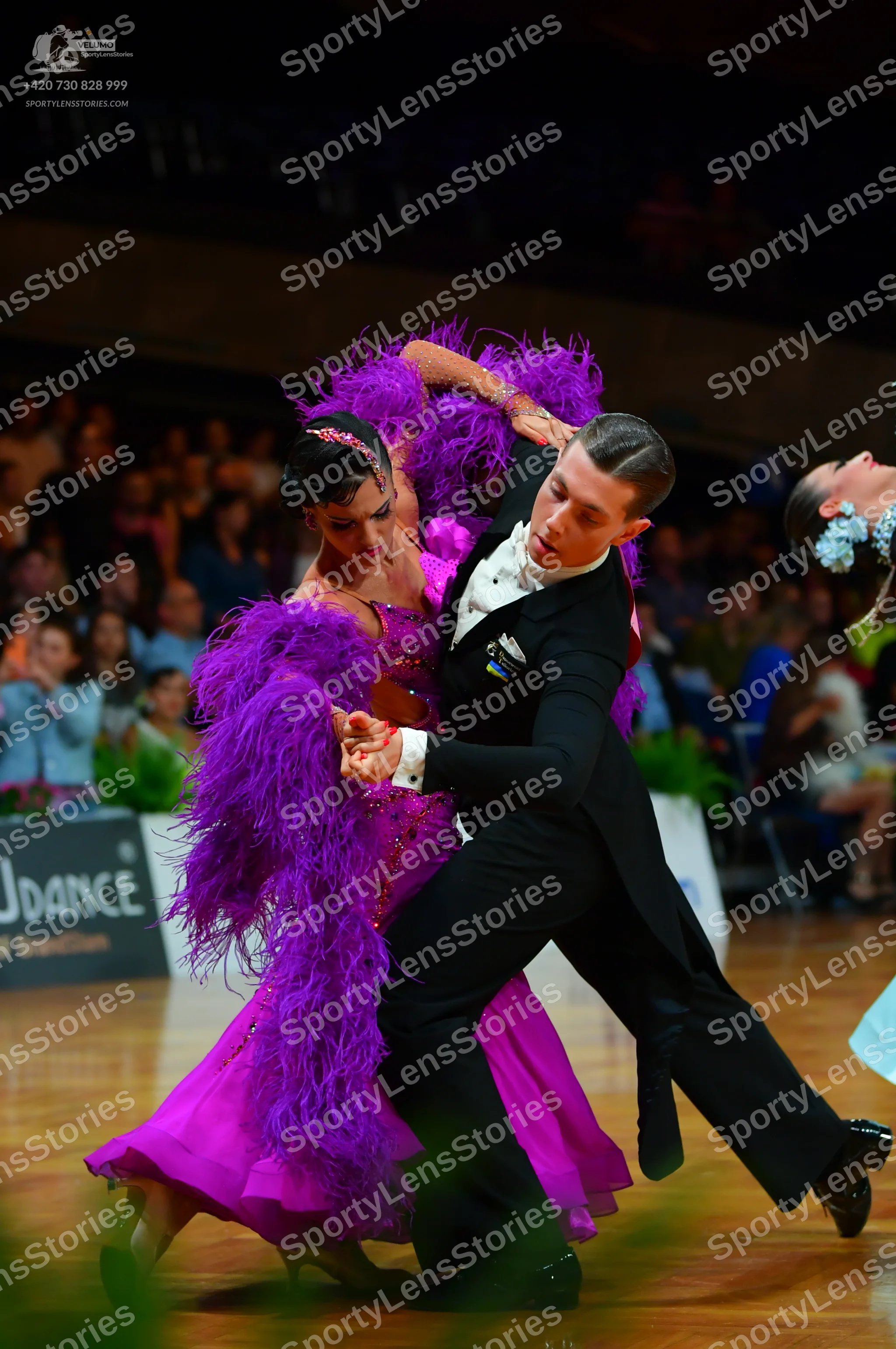 Dancesport competitor: Female dancer: vibrant purple ballroom dress featuring large, voluminous purple 