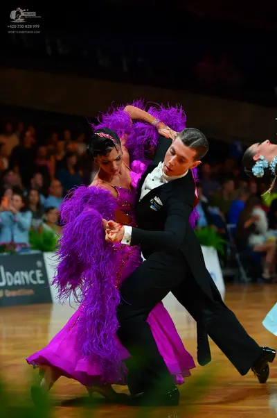 Dancesport competitor: Female dancer: vibrant purple ballroom dress featuring large, voluminous purple 