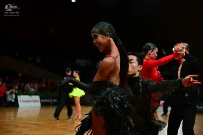 Dancesport competitor: Female dancer in foreground: black sequined latin dress with long black gloves