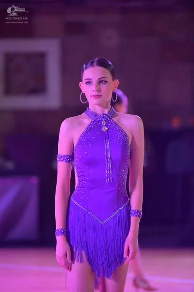 Dancesport competitor: Female dancer: purple latin dress with rhinestone embellishments, a halter neck 
