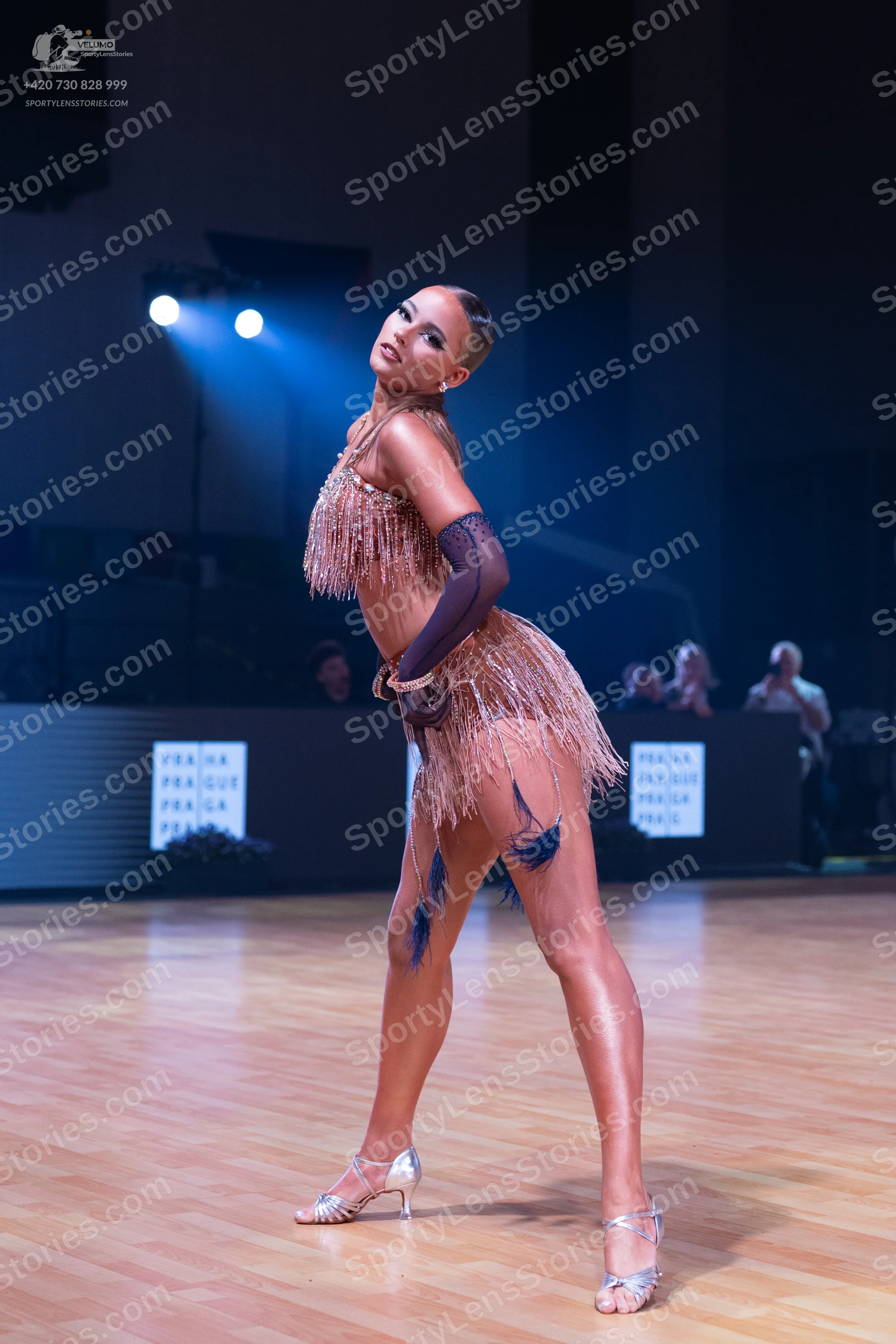 Dancesport competitor: Female dancer: bronze-colored Latin dance costume with fringe and sheer dark lon