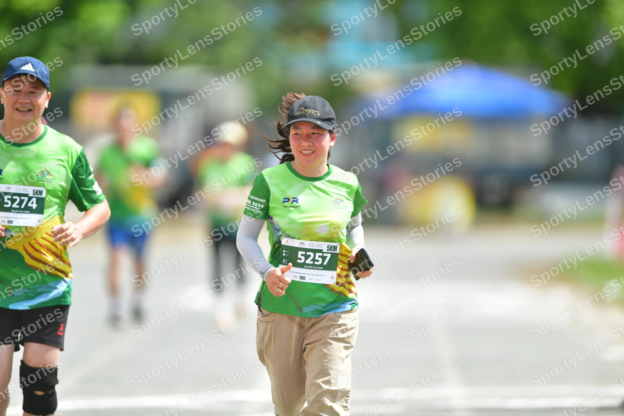 Marathon runner #5274, #5257: Runner 1: green and yellow jersey, black shorts, blue cap, black compression sle