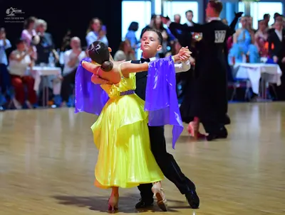 Dancesport competitor #28: Female dancer: yellow satin ballgown with sheer purple draped sleeves