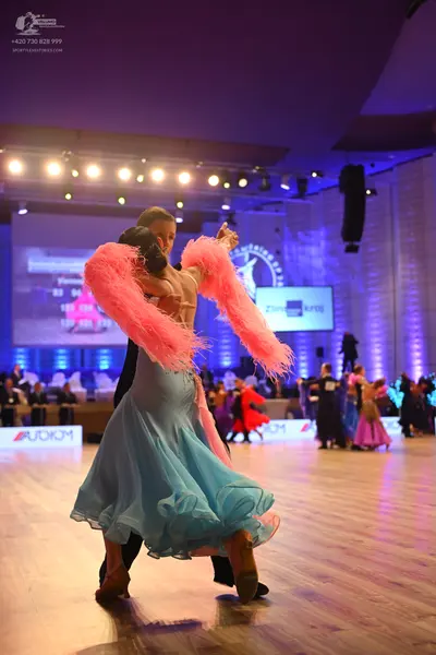 Dancesport competitor: Female dancer: light blue ballgown with a voluminous ruffled skirt and large pin