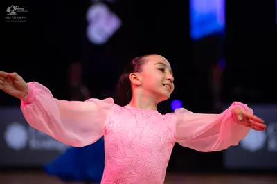 Dancesport competitor: Female dancer: light pink ballroom dress with a lace bodice and sheer, voluminou