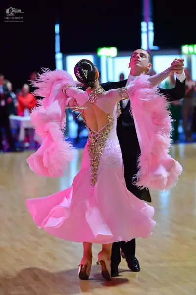 Dancesport competitor: Female dancer: light pink ballroom dress with long sleeves featuring voluminous 