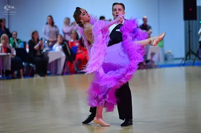Dancesport competitor: Female dancer: purple Latin dance dress with large lavender feathers and a sequi