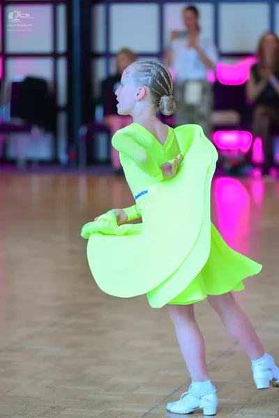 Dancesport competitor: Female dancer: bright neon yellow latin dress with long sleeves and a flowing sk
