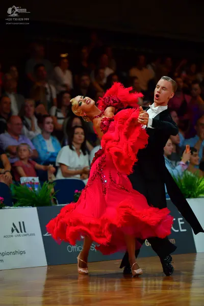 Dancesport competitor: Female dancer: red latin dress with voluminous ruffles and sequin embellishments