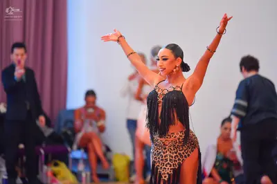 Dancesport competitor: Female dancer: leopard print Latin costume with long black fringe and gold brace