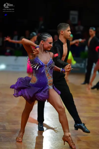 Dancesport competitor: Female dancer: purple Latin dance dress with sequins, mesh panels, and silver ac