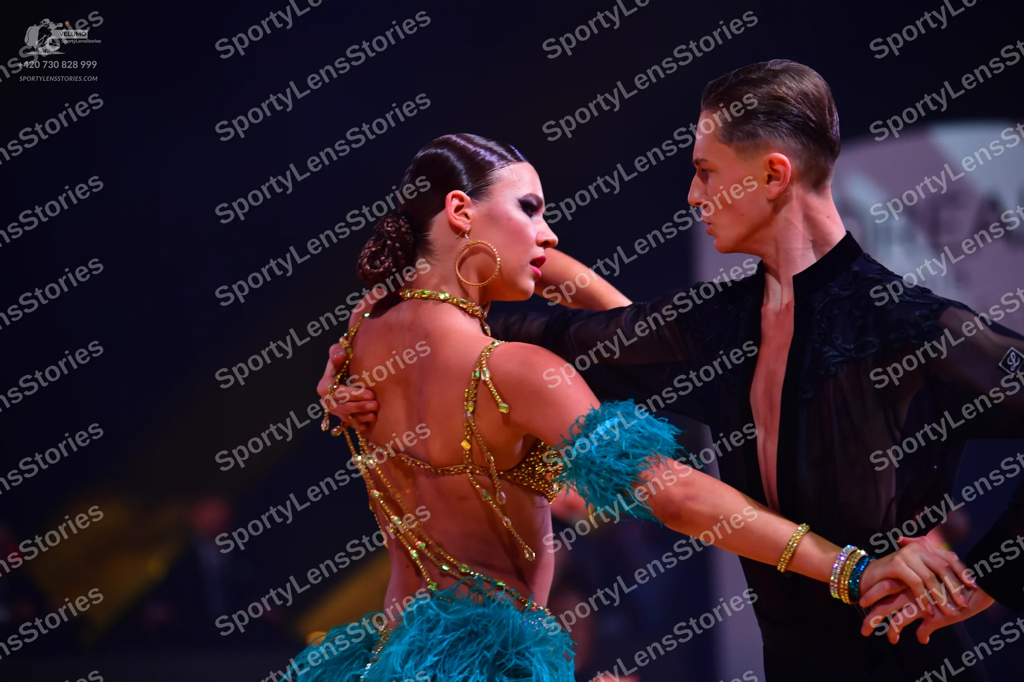 Dancesport competitor: Female dancer: gold sequined backless latin dress with turquoise feathered skirt