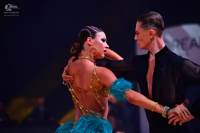 Dancesport competitor: Female dancer: gold sequined backless latin dress with turquoise feathered skirt