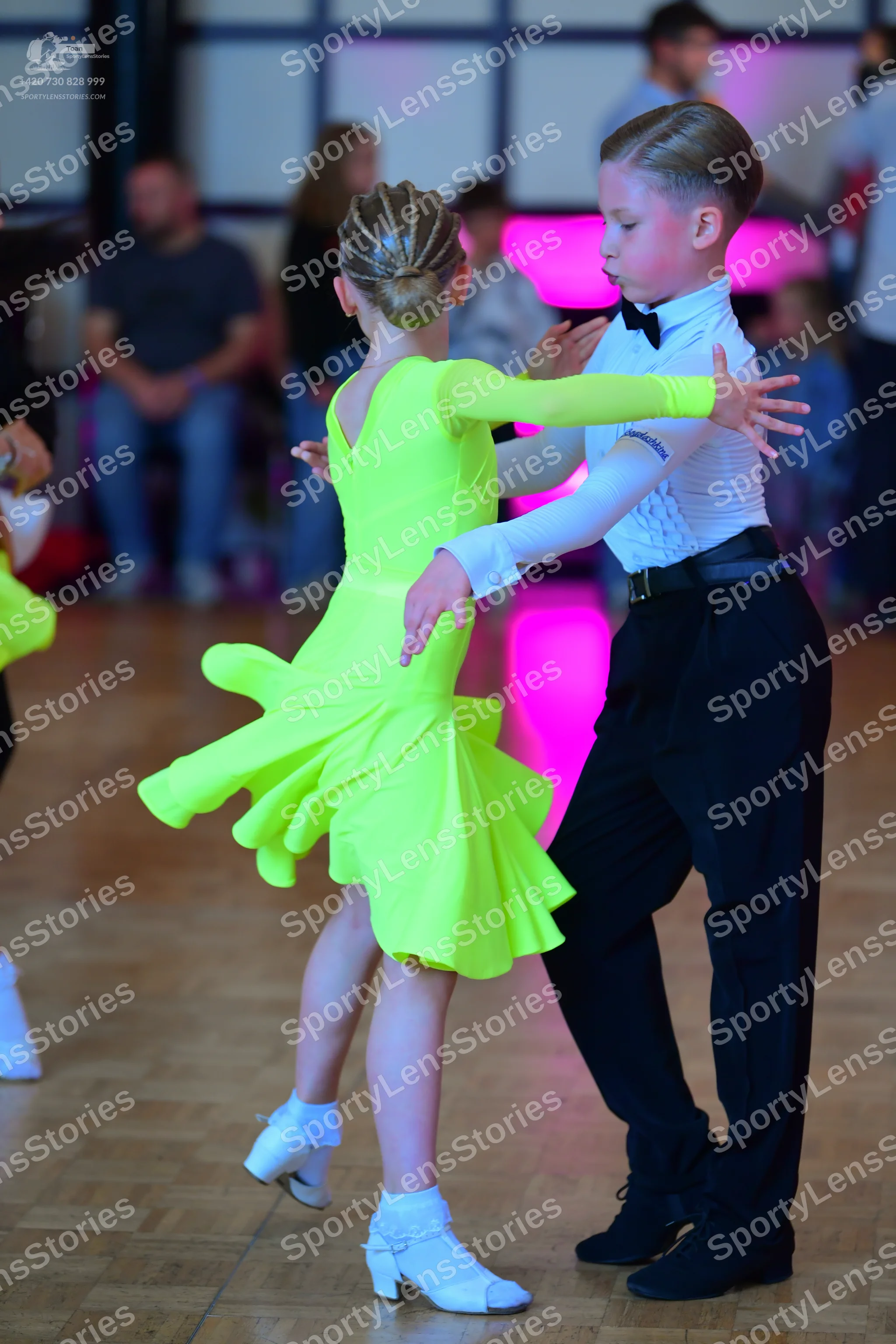 Dancesport competitor: Female dancer: neon yellow long-sleeved Latin dress with a flared skirt and whit