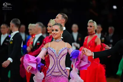 Dancesport competitor: Female dancer (foreground): lavender and pink sequined latin dress with large, c
