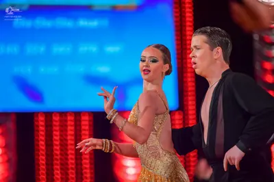 Dancesport competitor: Female dancer: gold sequined latin dress with gold bracelets on both wrists