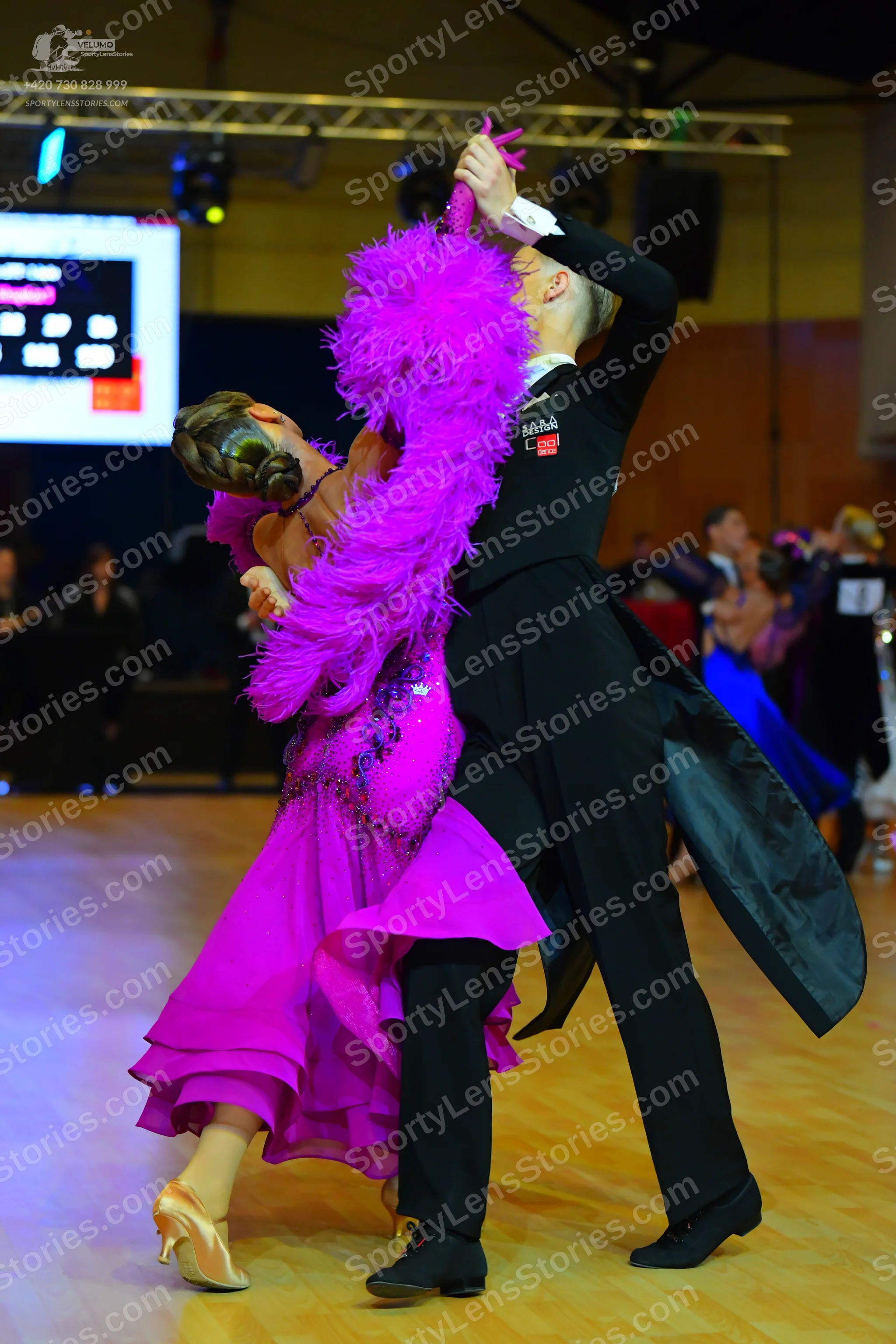 Dancesport competitor: Female dancer: bright pink ballroom dress with a voluminous ruffled skirt, featu