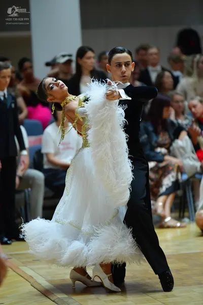 Dancesport competitor: Female dancer: white ballroom dress with gold lace embellishments and voluminous