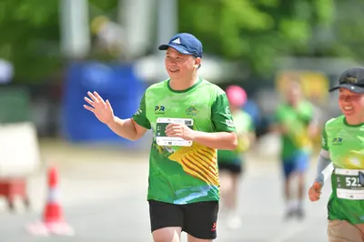 Marathon runner #52: Runner 1: green and yellow jersey, black shorts, blue cap
