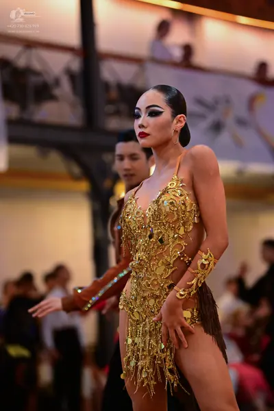 Dancesport competitor: Female dancer: gold Latin dress with heavy sequin and crystal embellishments, fe