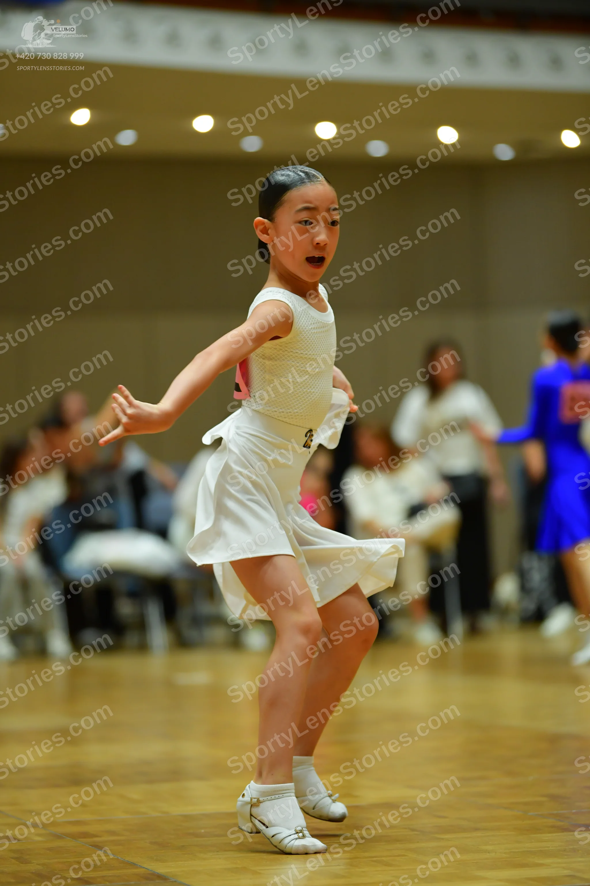 Dancesport competitor: Female dancer in foreground: white sleeveless Latin dance dress