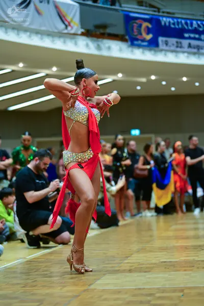 Dancesport competitor: Female dancer: red and silver sequined Latin dance costume with a halter-style t