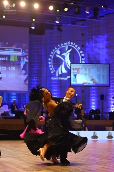 Dancesport competitor: Female dancer: black ballgown with a voluminous, flowing skirt and black feather