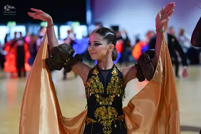Dancesport competitor: Female dancer: A black dress featuring intricate gold, yellow, and green sequin 