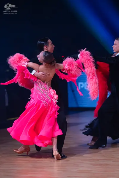 Dancesport competitor: Female dancer: bright pink Latin dance dress with large pink feather-like fringe