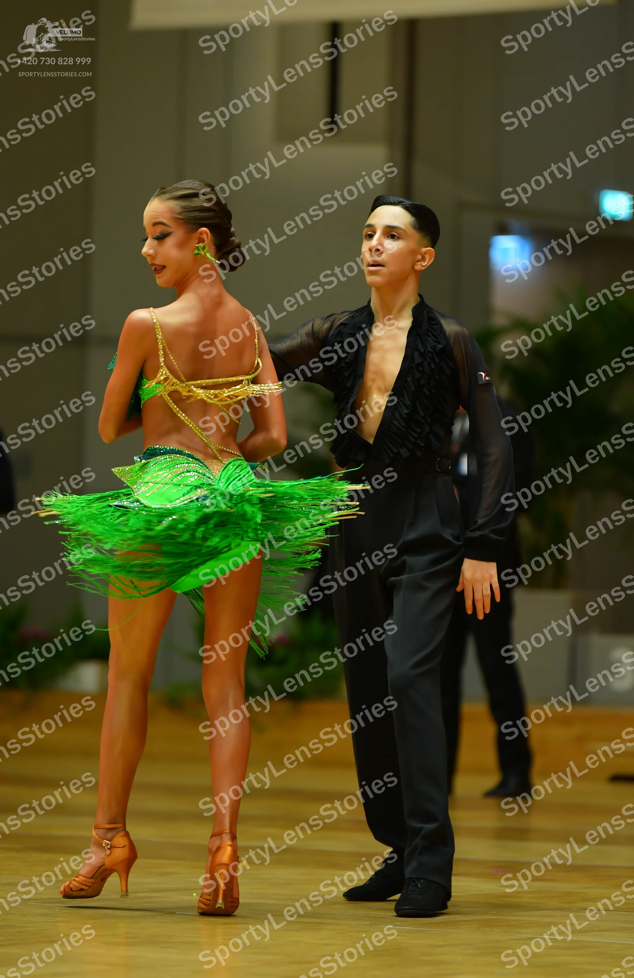 Dancesport competitor: Female dancer: vibrant green Latin dance dress with a sequined bodice and layere