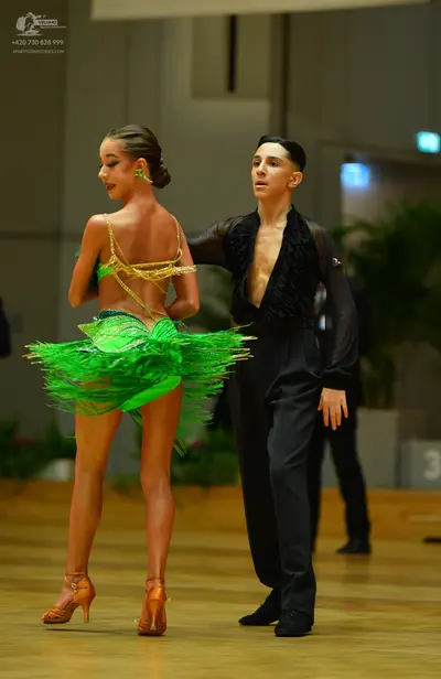 Dancesport competitor: Female dancer: vibrant green Latin dance dress with a sequined bodice and layere
