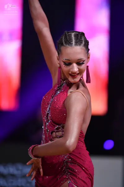 Dancesport competitor: Female dancer: burgundy Latin dance dress with sequins and cut-outs, featuring t