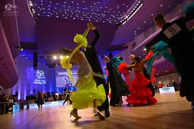 Dancesport competitor: Female dancer (foreground): lime green/yellow latin dress with fringe and sequin