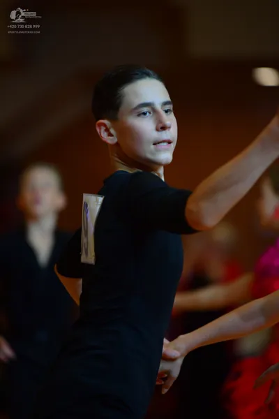 Dancesport competitor: Male dancer in foreground: black long-sleeved dance shirt