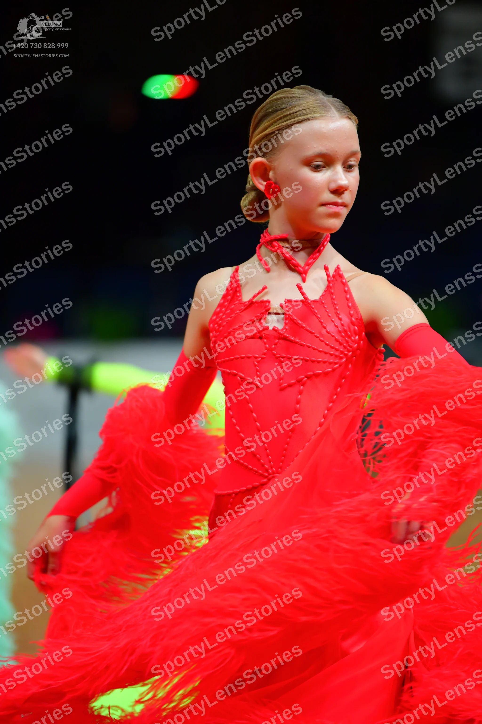 Dancesport competitor: Female dancer: red Latin dance dress with long sleeves, a red choker, and red ea