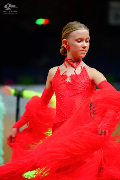 Dancesport competitor: Female dancer: red Latin dance dress with long sleeves, a red choker, and red ea