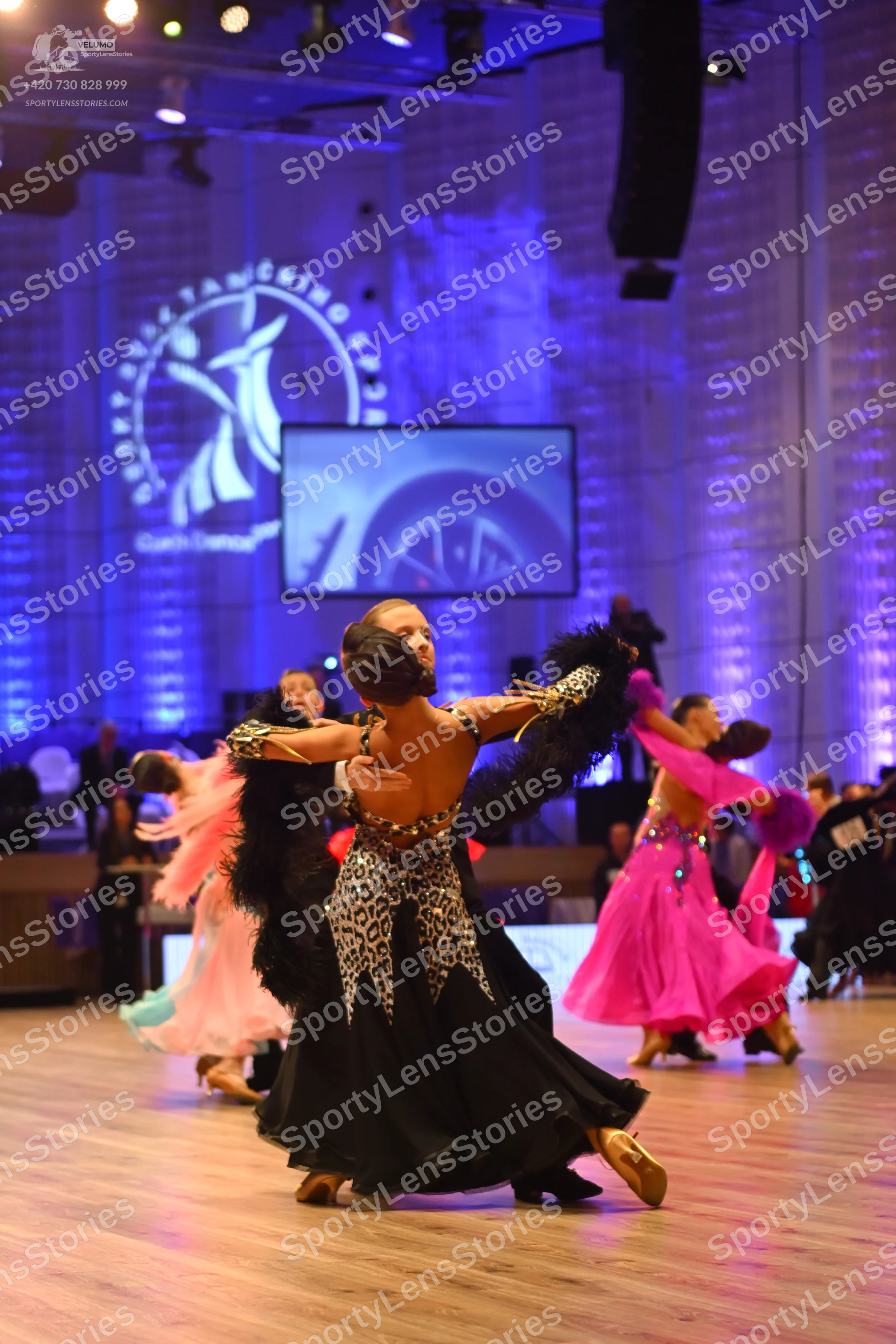 Dancesport competitor: Central female dancer: black and leopard print ballgown with a long, flowing ski