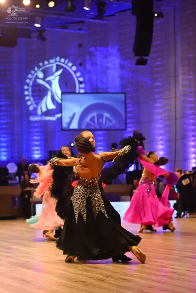 Dancesport competitor: Central female dancer: black and leopard print ballgown with a long, flowing ski