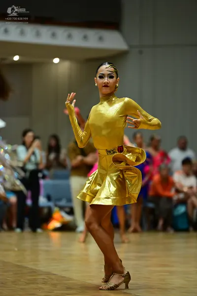 Dancesport competitor: Female dancer: gold metallic long-sleeved Latin dress with a high neck and a sho