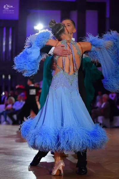 Dancesport competitor: Female dancer: light blue ballroom dress with a sequined bodice and large feathe