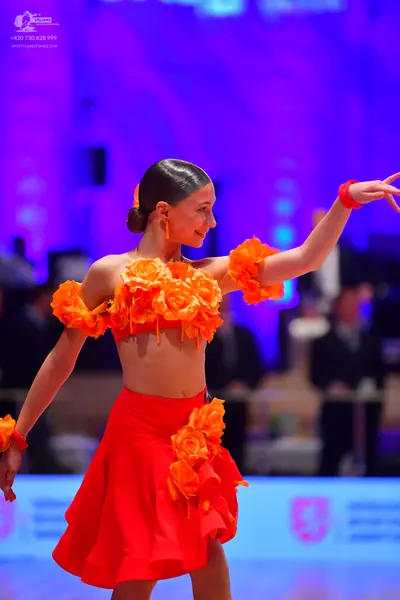 Dancesport competitor: Female dancer: two-piece red Latin costume consisting of a crop top and short sk