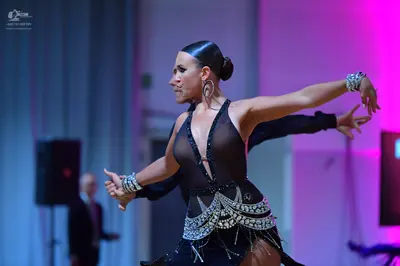 Dancesport competitor: Female dancer: black latin dress with a deep V-neckline and intricate silver/whi